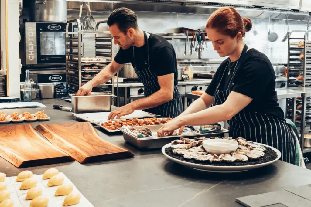 les compétences clé en hôtellerie-restauration ; des employés de restauration travaillent dans la cuisine du restaurant