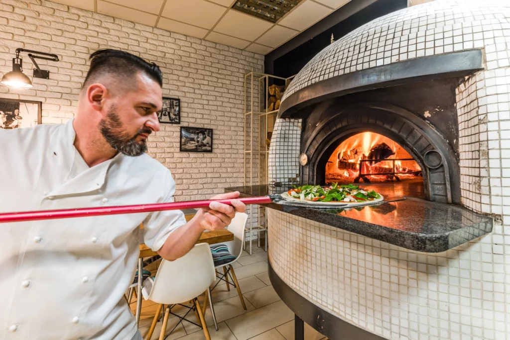 le métier de pizzaiolo : un pizzaiolo en train de mettre une pizza dans le four