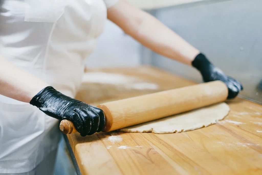 Métier de pâtissier·ère : un pâtissier roule sa pâte 