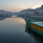 job en restauration à Lyon : soleil levant sur Lyon avec un bateau restaurant qui navigue sur le fleuve