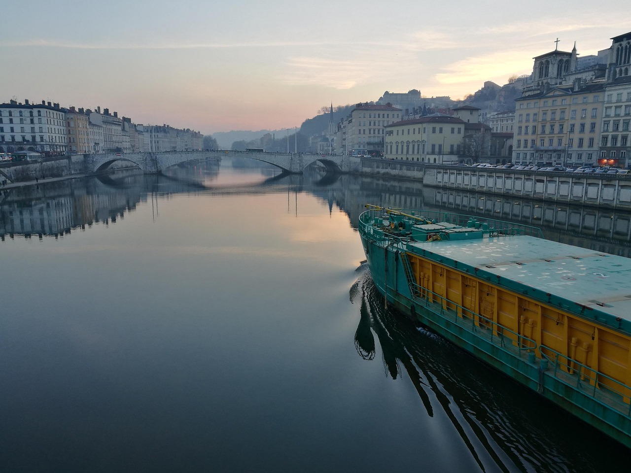 job en restauration à Lyon : soleil levant sur Lyon avec un bateau restaurant qui navigue sur le fleuve